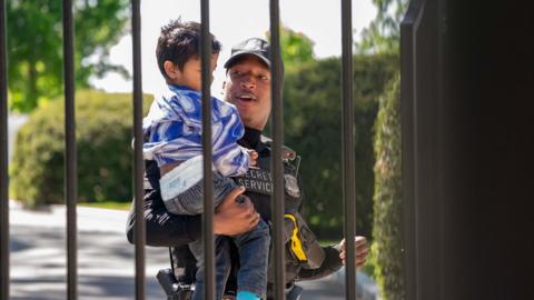 A police officer carries a child