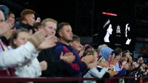 Aston Villa fans clap in tribute to the Queen