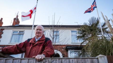 Ian with the Union Flag and the cCoss of St George in front of his house