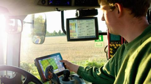 Farmer uses GPS in tractor