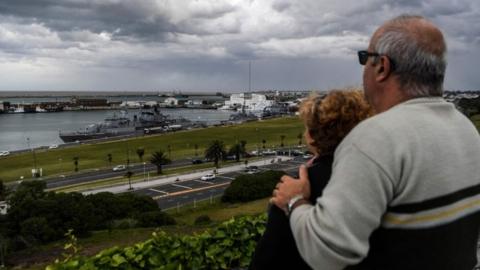 A couple looks at Argentina's Navy destroyer ARA Sarandi being refueled after taking part in the search of missing submarine ARA San Juan on November 20, 2017.