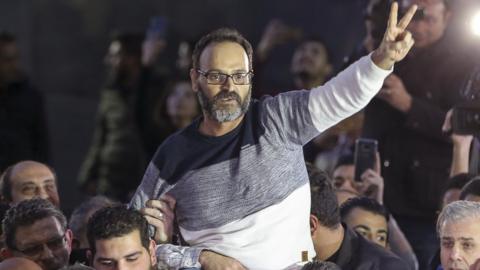 Lebanese actor Ziad Itani flashes a V for victory sign as relatives and friends carry him upon his return home in Beirut, 13 March 2018