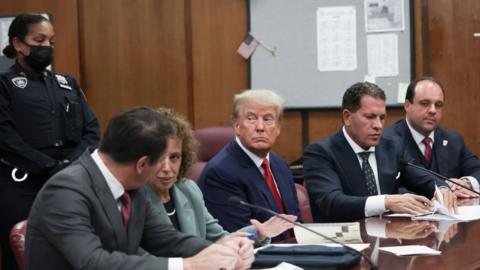 Trump, flanked by his lawyers, appears at his April 2023 arraignment in his hush money case.