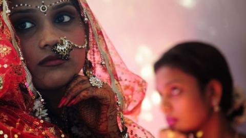 An Indian bride (L) waits with her sister (R) for her wedding ceremony.