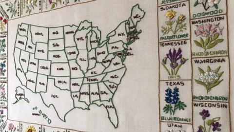 An image of Rita's quilt showing a map of the US and embroidered representations of each state around the outside.