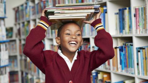 A girl in a library with books on her head