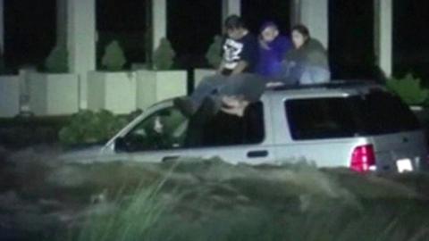 People stranded on car in flood water