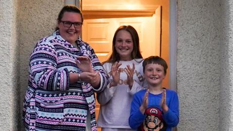 Family clapping at front door of their house in Saltburn-by-Sea