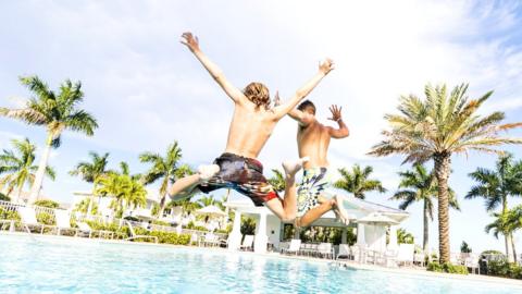 Boys jumping into swimming pool