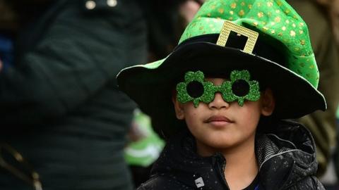 Little boy in bright green top hat at St Patrick's Day parade in Belfast 2019