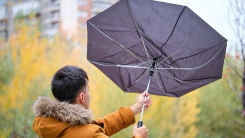 A man holding an inside out umbrella