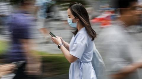 A photo taken using a slow shutter speed shows a woman wearing a protective mask as she walks through the financial district in Singapore, 07 February 2020.