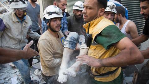 This file photo taken on July 23, 2016 shows Syrian civil defence volunteers, known as the White Helmets, carrying a body after digging it out from under the rubble of a building following a reported airstrike on the rebel-held district of al-Fardous in the northern city of Aleppo on July 23, 2016.