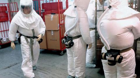 Pentagon officials wear protective suits as they inspect the quarantined mailroom