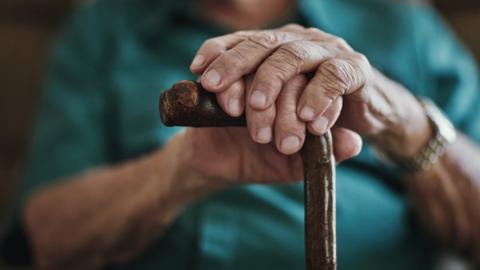 man's hands on walking stick