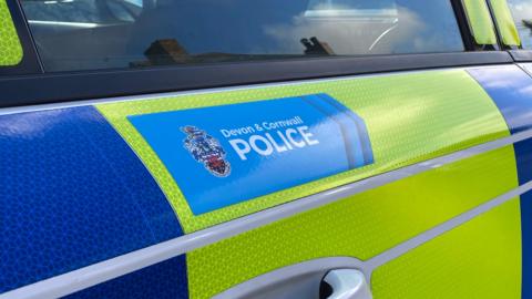 Generic shot of a police car door with a light blue sticker reading Devon and Cornwall Police.