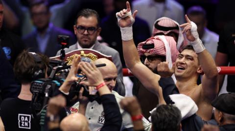 Dmitry Bivol celebrates in a crowd in the ring