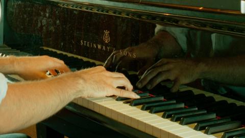 A close up of a man's hands playing a piano