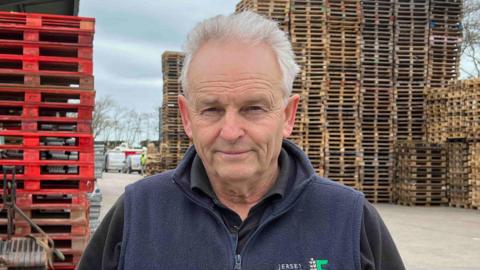 Doug Richardson, JFU president at his farm in St Ouen. Stacks of crates in the background and grey skies.