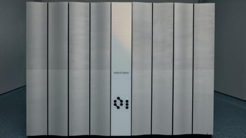 A front view of the new quantum computer Quartet. It has Oxford Ionics written in front. One of its buttons is light up in green.