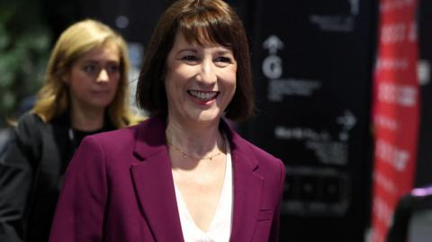 Chancellor Rachel Reeves smiles as she arrives at the Labour Party Conference in Liverpool wearing her self-purchased purple  suit designed by Hobbes