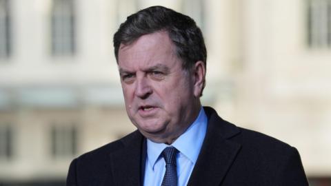 Mel Stride, a man, wearing a dark suit, blue shirt and dark tie.
