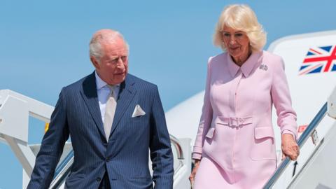 The King and Queen descend the stairs from their aircraft with the UK flag in view,as they arrive at the start of the their US trip.