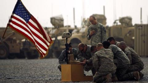 A photo taken on 14 September, 2010, showing US army officers with the 101st Airborne Division pay their respects by the boots, gun, helmet and dog-tags of US army First Lieutenant Todd W. Weaver displayed during a memorial ceremony