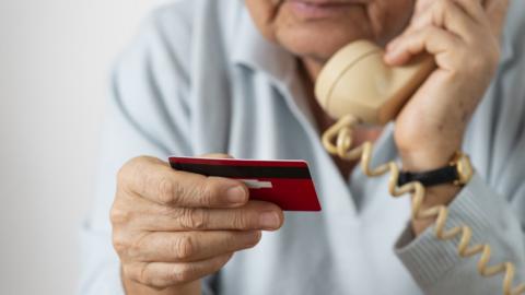 File photo of a woman holding bank card and speaking on phone