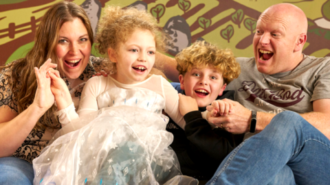 The family site together smiling - two children between two adults.