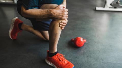 Man injured knee when doing exercises with kettlebell in gym - stock photo
