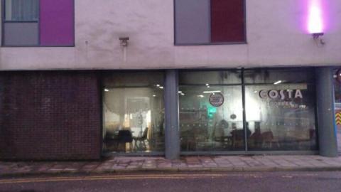 Costa Coffee shop on ground level of building - smoke damage can be seen around the windows.