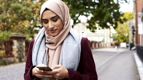 Muslim woman looks at her phone