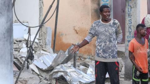 Residents pause to assess the damage at the site of an attack at the Palm Beach Hotel in Mogadishu on 10 June.