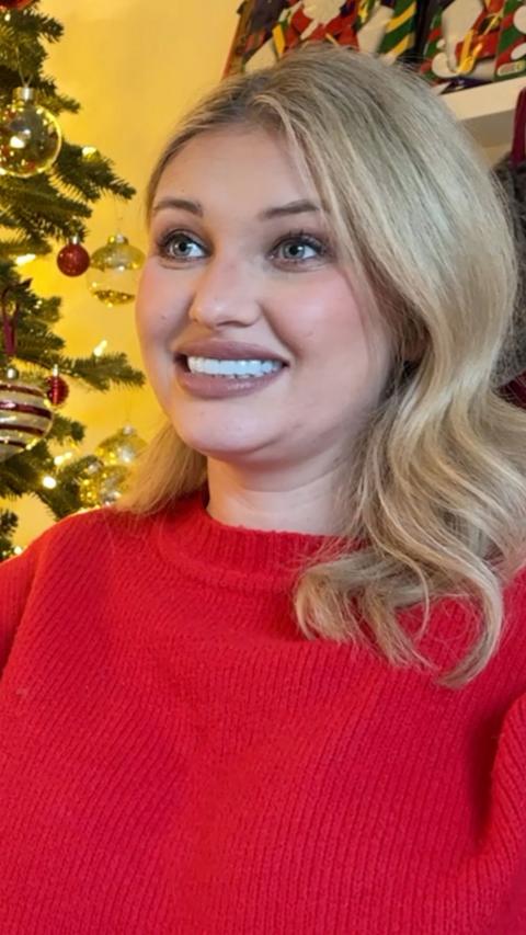 Amy Hart, a blonde woman in a red jumper looks at camera