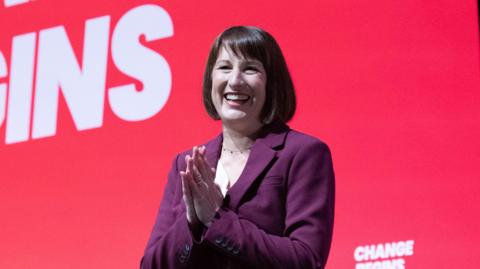 Rachel Reeves smiling with hands clasped in front of conference slogan