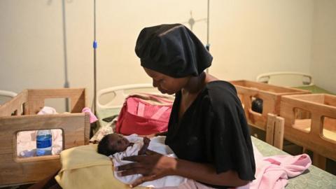 A woman holds a malnourished baby