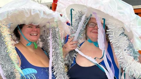 Two women dressed as jellyfish with tinsel hanging off their headpieces