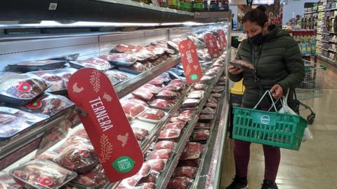 A woman holds packaged meat in a supermarket amid soaring inflation in Argentine.