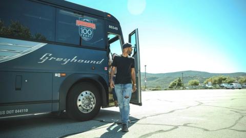 Man standing next to Greyhound bus