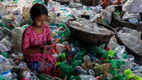 A girl sorts through plastic recycling in Bangladesh