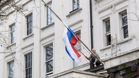 Official disentangling Russian flag outside its London embassy