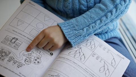 File photo of a young child's hand pointing at a work book