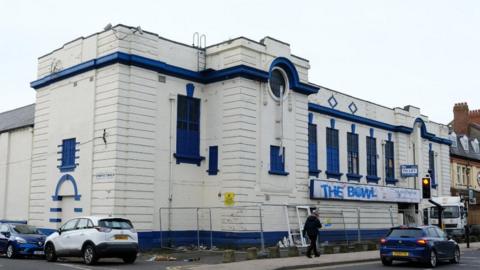 The old building, painted white with blue trim