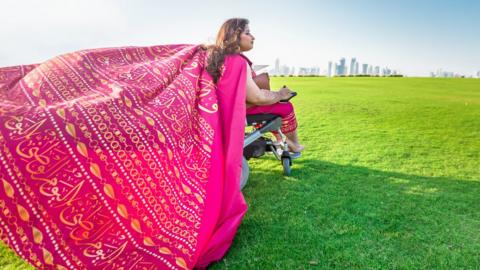 Nawaal Akram in wheelchair, wearing a flowing pink shawl.