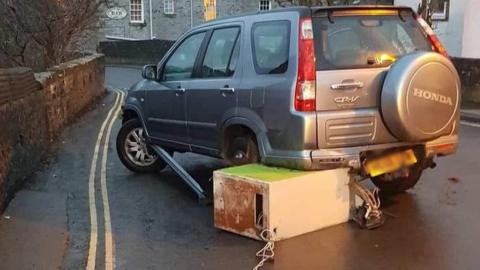 ATM wedged beneath parked car