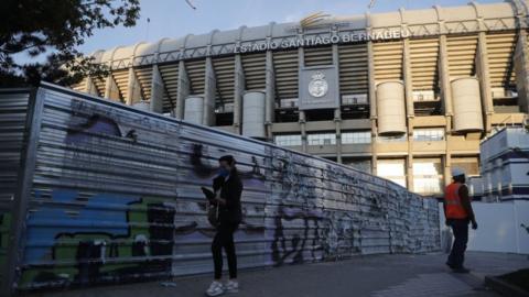 Fan in mask walks by Real Madrid's Bernabeu Stadium