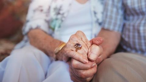 Elderly man and woman holding hands