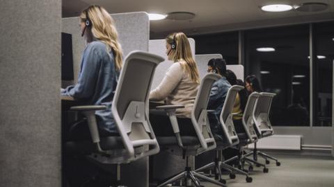 male and female customer service representatives sitting on chairs working in call centre