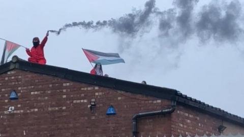 Pro-Palestinian protesters on the roof of the Elbit factory in Shenstone